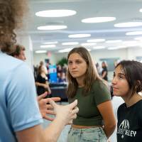 Scholar giving poster presentation to two students.